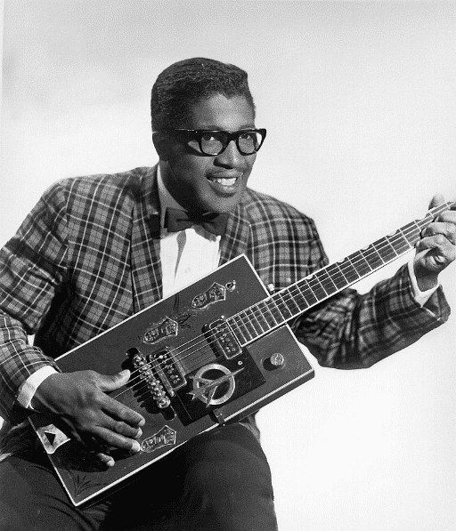 a black and white photo of bo diddley playing his guitar