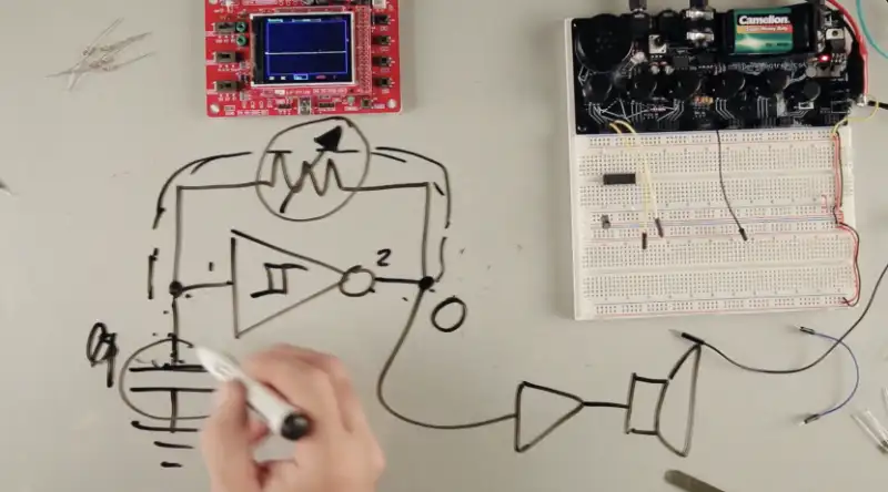 a top-down view of a breadboard synth with a circuit schematic drawn in whiteboard marker on the table surface
