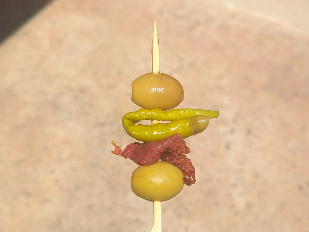 A pepper on a skewer that appears yellow to some and green to others